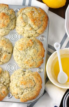 freshly baked muffins sitting on a baking tray next to lemons and honey