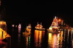 several boats in the water at night with lights on them