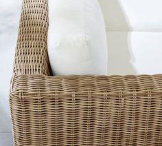 a wicker chair with white pillows on it's seat cushion and back rest