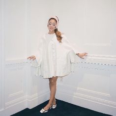 a woman standing in front of a white wall