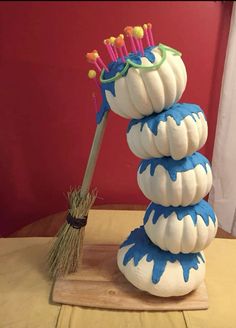 a stack of white pumpkins sitting on top of a wooden table next to a broom