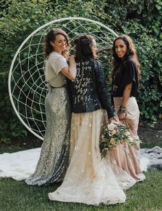 three women standing next to each other in front of a circular object