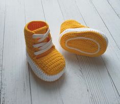 a pair of yellow crocheted shoes sitting on top of a white wooden floor