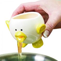 a person pouring water into a pot with a yellow ducky on it's side