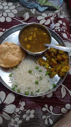 a silver plate topped with rice and veggies next to a bowl of soup