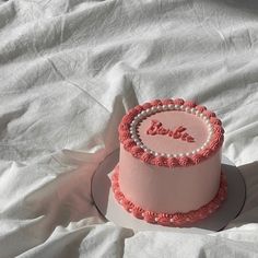 a pink cake with the word love written on it sitting on top of a white sheet