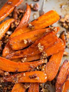 roasted carrots and pecans on a baking sheet with a serving spoon in it