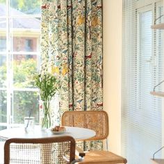 two chairs and a table in front of a window with curtains on the windowsill