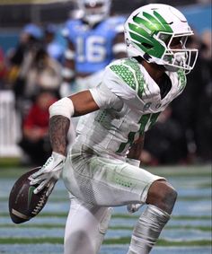 a football player is running with the ball in his hand and wearing a white uniform