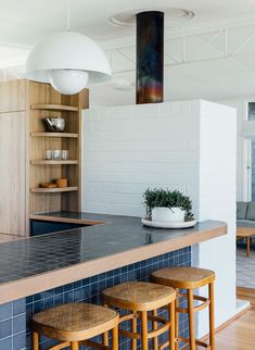 a kitchen with blue tiles and wooden stools