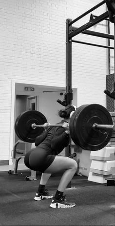 a woman is squatting down with a barbell