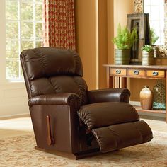 a brown recliner chair sitting in front of a window