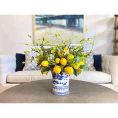 a blue and white vase filled with oranges on top of a table