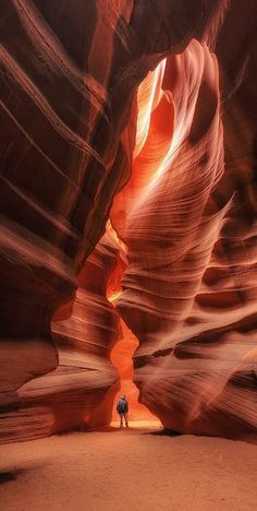 a person standing in the middle of a narrow slot between two large canyons,