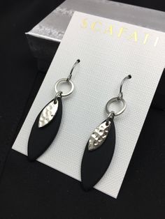 "The almond shaped drop is made of black sea glass and is light weight. The overlapping piece and hoops are plated with a silver alloy. The ear wires are surgical steel with rubber back stoppers to keep the earrings from falling off. All metals used are lead safe. The full length of the earring from the top of the hook down is 2\". Also available is a matching necklace, You have your choice between the following: 1) Sea Glass Black Earrings 2) Sea Glass Necklace- 16\" or 18\" 3) Sea Glass Neckla Black Neck, Sea Glass Earrings, Almond Shaped, Hammered Metal, Sea Glass Necklace, Earrings Black, Black Earrings, Black Sea, Matching Necklaces