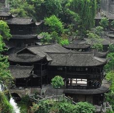 an old chinese building surrounded by trees and greenery in the mountainside with stairs leading up to it