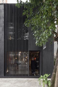 an entrance to a building with black slats on the side and trees in front