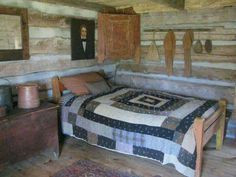 a bed in a room with wooden walls and flooring next to a chest of drawers