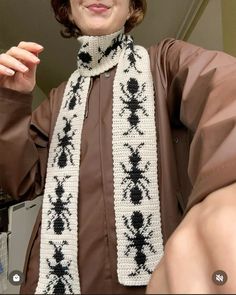 a woman wearing a scarf with black and white designs on it, posing for the camera