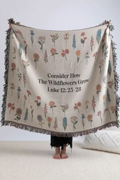 a woman standing under a white blanket with flowers on it and the words consider how the wildflowers grow