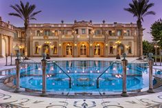 a large mansion with a pool surrounded by palm trees