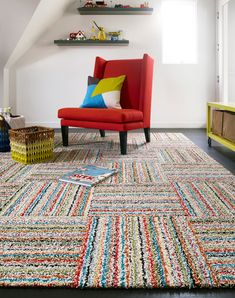 a living room with a red chair and colorful rug