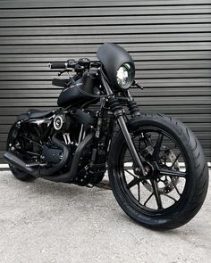 a black motorcycle parked in front of a garage door