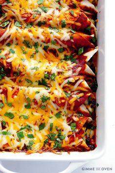 a white casserole dish filled with cheesy chicken enchiladas