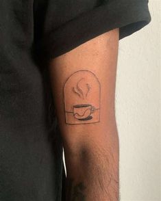 a man's arm with a coffee cup tattoo on the left side of his arm