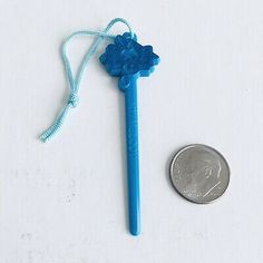 a blue plastic toothbrush next to a penny on a white surface with a string