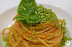 a white plate topped with pasta covered in sauce and garnished with green leaves