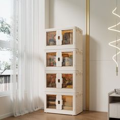 a white cabinet with three glass doors in front of a window