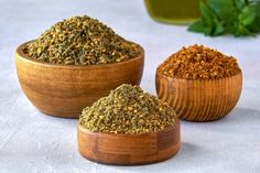 three wooden bowls filled with different types of spices