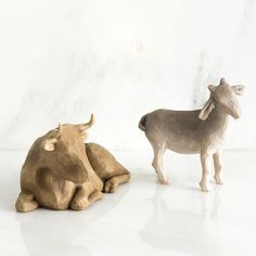 two wooden animals sitting next to each other on a white surface with one animal looking at the camera