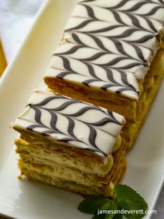 two pieces of cake sitting on top of a white plate next to a green leaf