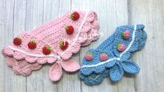 two crocheted hats with strawberries on them sitting next to each other in front of a wooden surface