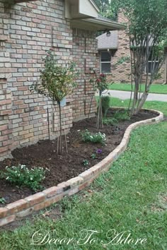 a brick wall and flower bed in front of a house