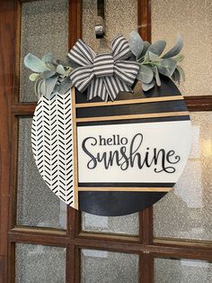 a hello sunshine sign hanging on the side of a door with leaves and ribbon around it