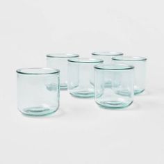 six glasses are lined up on a white surface