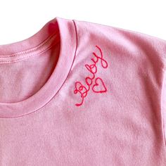 a pink t - shirt with the word dog embroidered on it