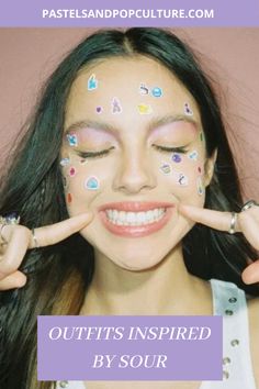 a woman with her hands in front of her face and painted stickers on her cheeks