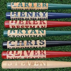 four baseball bats with names on them sitting in the grass next to some green grass