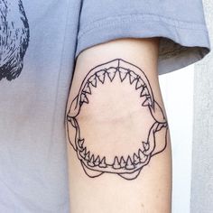 a man with a tattoo on his arm has a shark's teeth in the shape of a circle