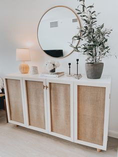 a white sideboard with some plants and a mirror