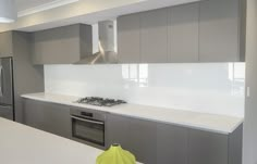 a modern kitchen with stainless steel appliances and white counter tops, along with gray cabinets