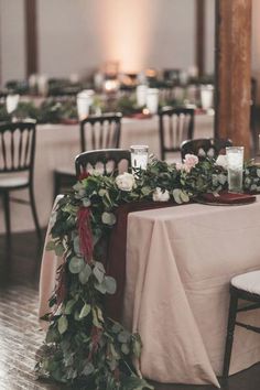 the table is set with candles and greenery for an elegant wedding reception at this venue