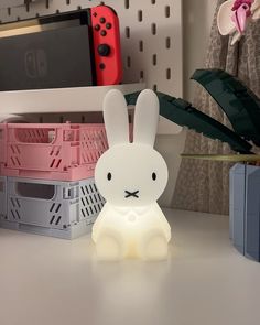 a white rabbit lamp sitting on top of a table next to a nintendo wii game controller