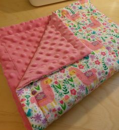 a pink blanket laying on top of a wooden floor next to a computer mouse and keyboard