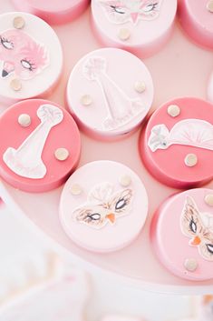 pink and white decorated cookies sitting on top of a cake platter with decorative designs