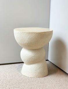 a white vase sitting on top of a carpeted floor next to a wall and door